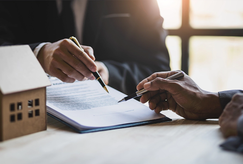 A person is signing papers on top of a table.